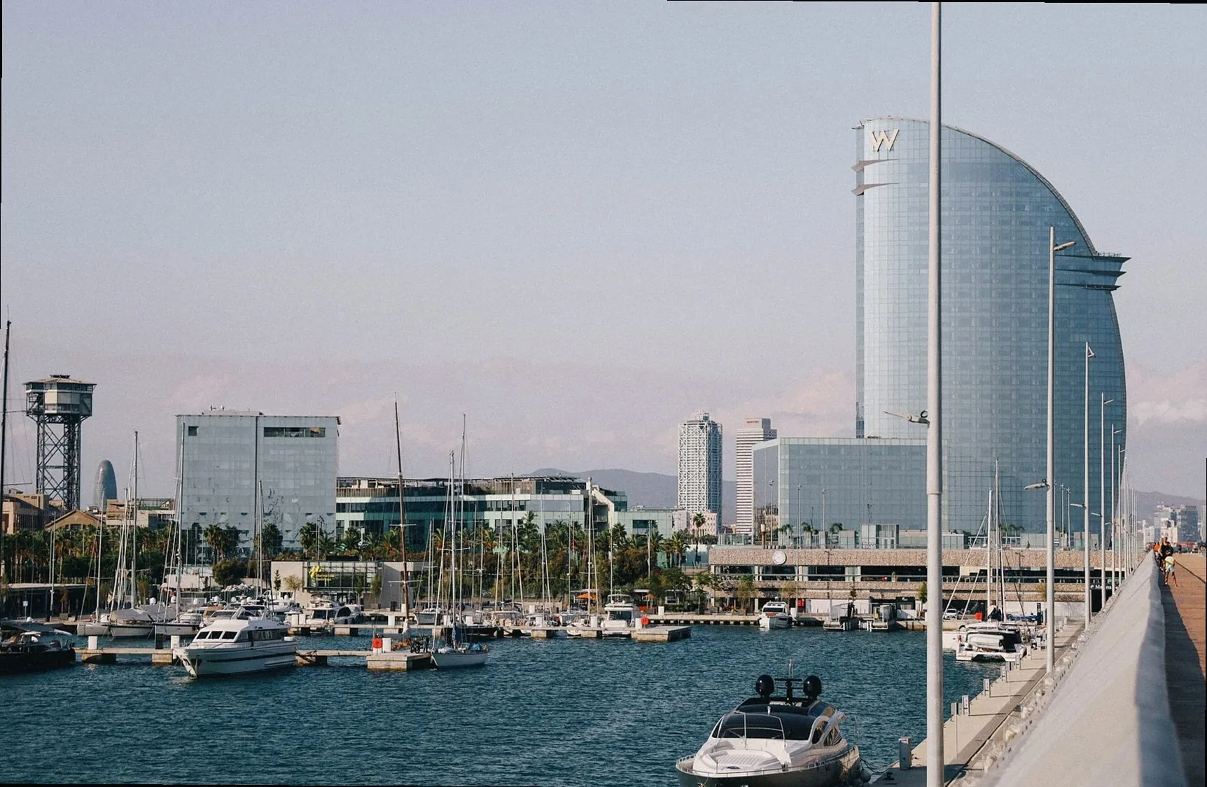 Modern architecture and boats in Barcelona's scenic harbor, with iconic skyline views.
